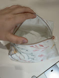Load image into Gallery viewer, Cotton Bloom cream lining held open by hand on original table
