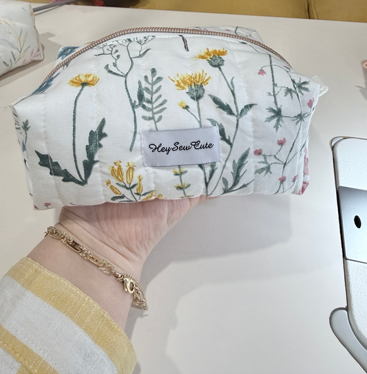 Daily Muse wildflower handmade makeup bag held in hand with original table and natural shadow
